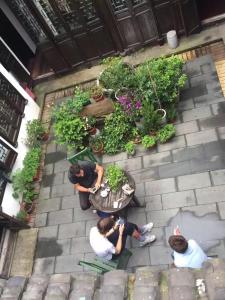 un groupe de personnes assises sur un patio avec des plantes dans l'établissement Hofang Guest House, à Hangzhou