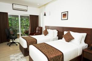 ein Hotelzimmer mit zwei Betten und einem Stuhl in der Unterkunft THE RUNWAY HOTEL in Kochi