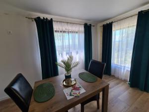 a dining room with a wooden table with chairs and curtains at Bella Vista Bungalow in Turda