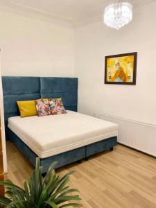 1 cama con cabecero azul en una habitación en Platános Apartman Tata, en Tata