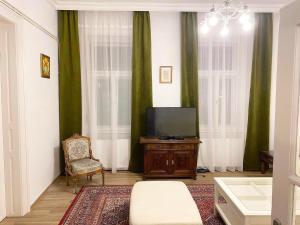 a living room with a tv and a chair at Platános Apartman Tata in Tata