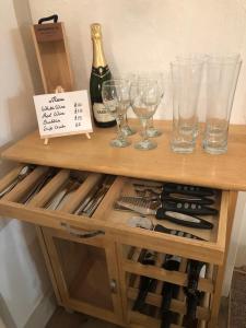 einen Holztisch mit Weingläsern und Weinflaschen in der Unterkunft Beautiful Barn Conversion, 3 Bed, hot tub, sauna, gym, enclosed garden in Ryde