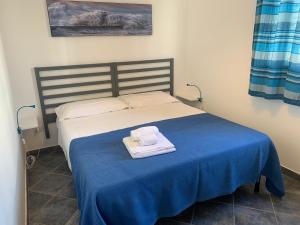 a bed with a blue blanket and two towels on it at Le Casuzze del Residence Lido Burrone in Favignana