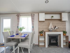a dining room with a table and a fireplace at Moondunes - Pwllheli in Pwllheli