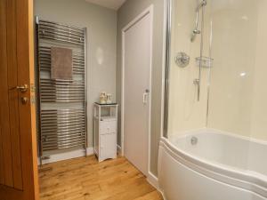 a white bathroom with a tub and a shower at 1 Springfort Cottages in Penrith +29 photos