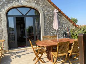 uma mesa de madeira com cadeiras e um guarda-sol num pátio em La Grange aux portes du Touquet, 1 ou 2 ch, terrasse, jardin, parking em Cucq