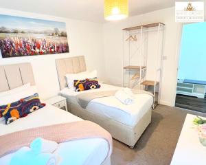 a bedroom with two beds and a painting on the wall at Contractors 2 Bed Apartment in Stevenage near Asda By White Orchid Property Relocation Leisure & Business in Stevenage