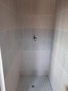 a bathroom with a shower with a tiled floor at Central Cottages in Soweto
