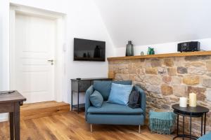 a living room with a blue chair and a stone wall at Neue Dachwohnung im Herzen von Gönnheim 