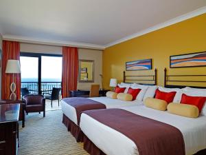 a hotel room with two beds and a balcony at Corinthia St George's Bay in St. Julianʼs