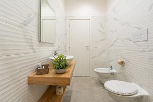 a white bathroom with a toilet and a sink at Baia Flegrea Meublè in Bacoli