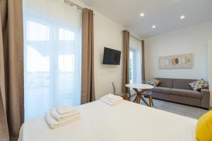 a bedroom with a white bed and a couch at Baia Flegrea Meublè in Bacoli