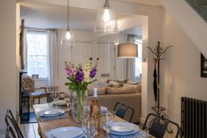 a dining room table with a vase of flowers on it at Nutshell Cottage in Lymington