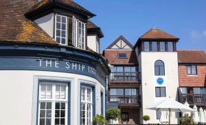 a white building with a blue clock on it at Nutshell Cottage in Lymington