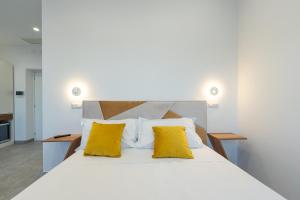 a bedroom with a white bed with yellow pillows at Baia Flegrea Meublè in Bacoli