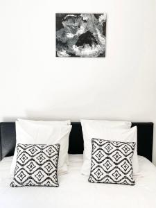1 cama con almohadas blancas y una foto en la pared en T2 NEUF TERRASSE PRES des PLAGES, en Saint-Cyr-sur-Mer