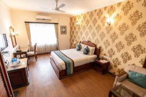 um quarto com uma cama e uma cadeira num quarto em The Lindsay em Calcutá