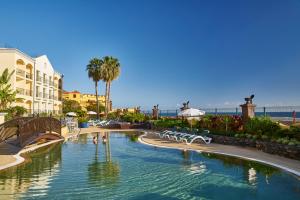 einen Pool in einem Resort mit Palmen in der Unterkunft Hotel Porto Santa Maria - PortoBay - Adults Only in Funchal