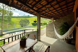 eine Veranda mit Hängematte und Tisch und Stühlen in der Unterkunft Villa Ayê Socorro SP - Pousada Petfriendly in Socorro