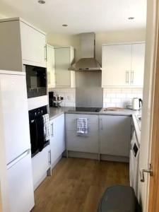 een keuken met witte kasten en een zwarte oven bij Modern 4 bed home, 30 minute walk from City Centre in York