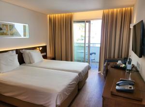 カニコにあるホテル ロカ マールのベッド、デスク、テレビが備わるホテルルームです。