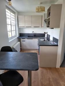 eine Küche mit weißen Schränken und einer schwarzen Arbeitsplatte in der Unterkunft Location saisonnière appartement situé à Saumur in Saumur