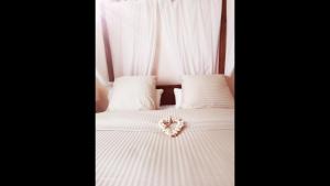 a white bed with white pillows and a flower on it at Ness Home A Beautiful Village House in Maraussan