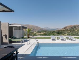 a pool with chairs and a view of the mountains at Eolides Villas , Quite Idyll of Rural Bliss,By ThinkVilla in Lambiní