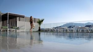 una mujer está de pie junto a una piscina en Eolides Villas , Quite Idyll of Rural Bliss,By ThinkVilla en Lambiní
