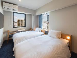 a hotel room with two beds and a window at Sotetsu Fresa Inn Sendai in Sendai