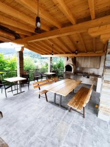 a large patio with wooden tables and a fireplace at Pensiunea ANCA in Statjunea Borsa