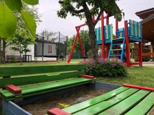 un banco verde en un parque con parque infantil en Villa Jerman, en Konska