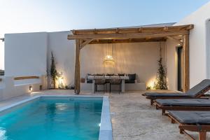 a pool with chaise lounge chairs and a table with a piano at Golden Sand Villas with Private Pool in Vívlos