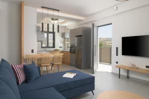 a living room with a blue couch and a kitchen at Eolides Villas a mythical escape in Lambiní
