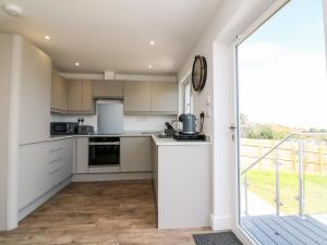 cocina con armarios blancos y ventana grande en 65 Channel View, en Ilfracombe