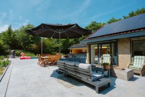 un patio con banco y sombrilla en West Nieuwlandseweg 25A - Ouddorp - with Pool - NOT FOR COMPANIES en Ouddorp