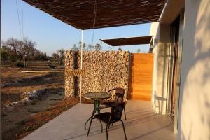 un patio con 2 sillas, una mesa y una pared en giardino del tempo en Merine