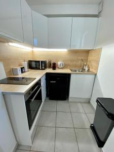 a small kitchen with white cabinets and a sink at Superbe appartement 2 pièces, plein centre ville. in Montlhéry