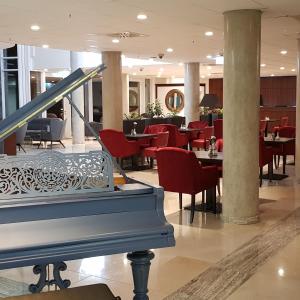 a lobby with a restaurant with red chairs and a piano at Hotel Schopenhauer Hof in Frankfurt/Main