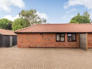 a red brick house with a brick driveway at The Nest Box in Diss