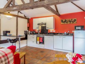 a kitchen with orange walls and white appliances at The Nest Box in Diss