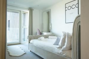 a white bedroom with a bed and a large window at Luxury beach apartment in Perranporth