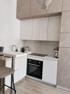 a kitchen with white cabinets and a black oven at Studio apartment INDIGO in Osijek
