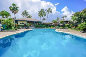 una gran piscina frente a una casa con palmeras en Mauna Kai 6B, en Princeville
