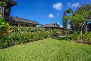un patio de una casa con césped verde y flores en Mauna Kai 6B, en Princeville