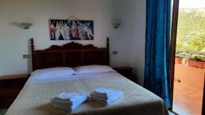 Villagrande StrisailiにあるFattoria Nuraghe Murtarbaのベッドルーム1室(ベッド1台、タオル2枚付)