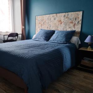 a blue bedroom with a bed with a blue comforter at La Demeure de Cathy in Agneaux
