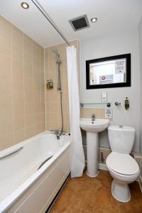 a bathroom with a toilet and a sink and a bath tub at Lamb & Flag Inn in Abergavenny