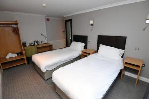 ein Hotelzimmer mit 2 Betten mit weißer Bettwäsche in der Unterkunft Lamb & Flag Inn in Abergavenny