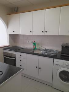 eine Küche mit weißen Schränken, einer Spüle und einem Geschirrspüler in der Unterkunft Casa sol y mar in Vera